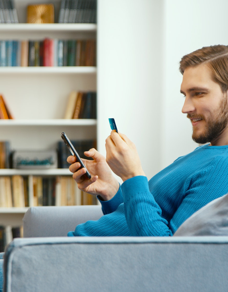 young-man-looks-at-bank-card-in-hand-and-enters-digits-to-smartphone-noa-bank